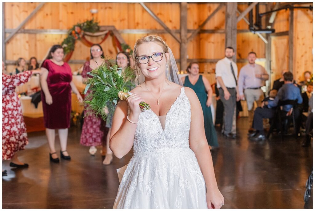 bride tossing her bouquet at fall wedding reception at the Village Barn