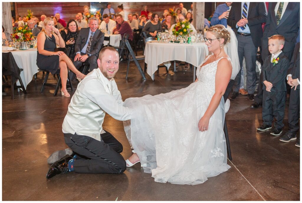 groom getting the garter off the bride's leg on the dance floor 