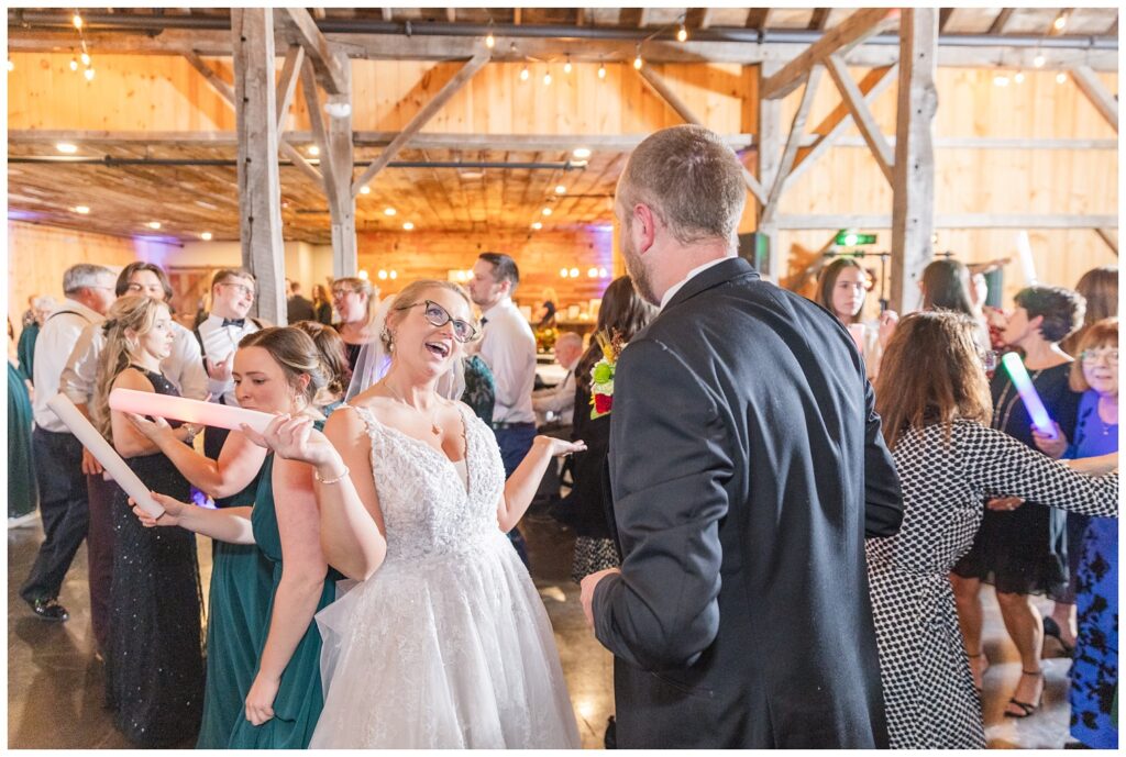 bride and groom dancing with light-up foam wands during fall reception