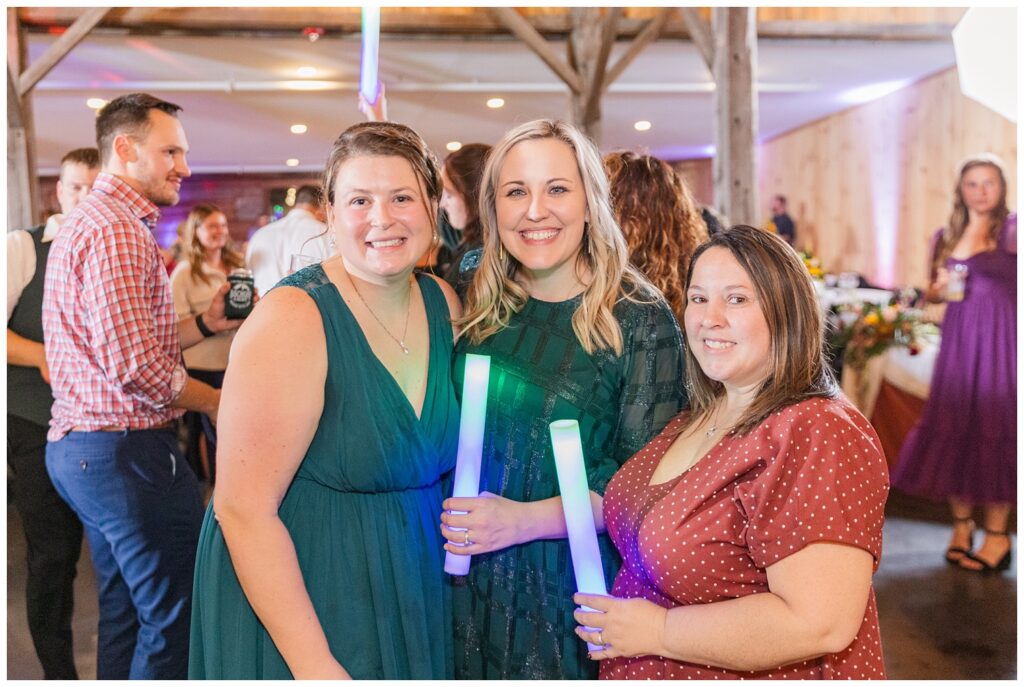 wedding guests posing with light-up foam wands on the dance floor 