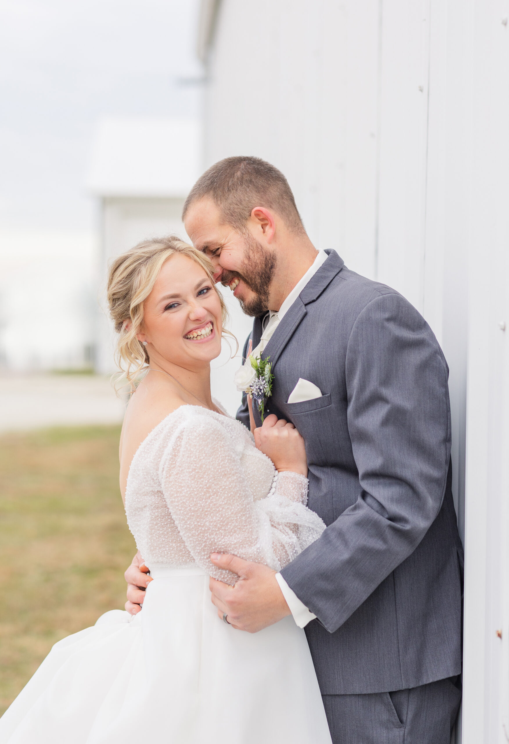 Fremont, Ohio wedding couple leaning against a white barn