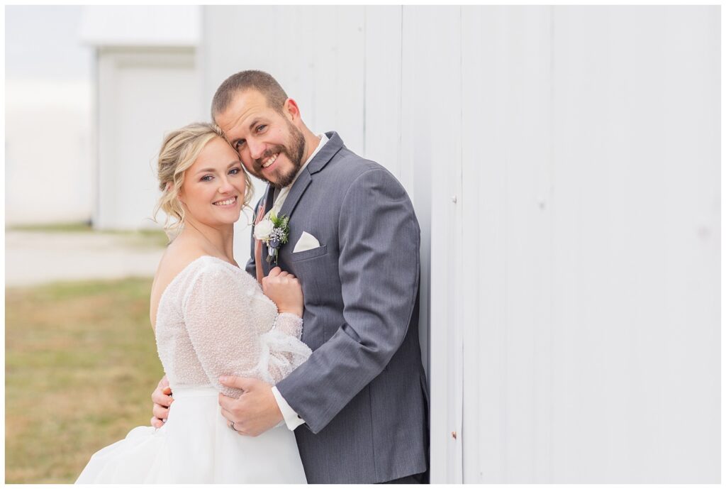 bride and groom posing on the bride's family farm in winter 