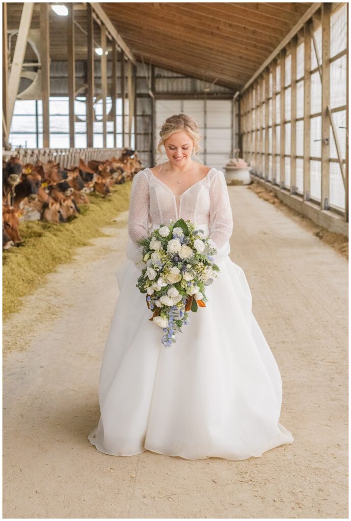 bride looking down at her bouquet while posing inside the groom's family barn