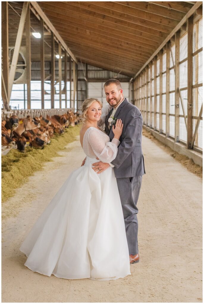 bride and groom posing inside the cow barn at the groom's farm