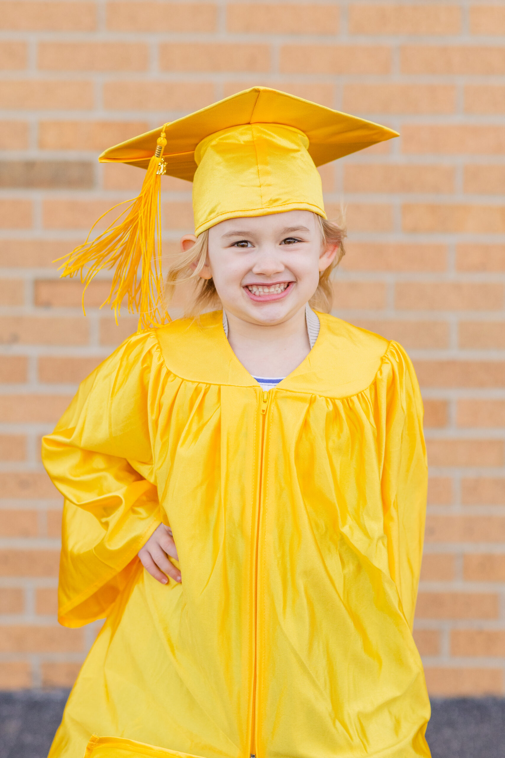 little girl wearing a bright yellow graduation cap and gown