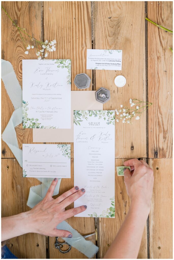 Tiffin, Ohio photographer laying out a wedding flat lay on a wood floor