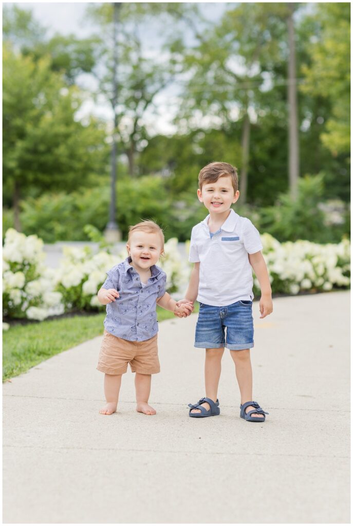 two brothers holding hands posing in front of flowers in Tiffin, Ohio