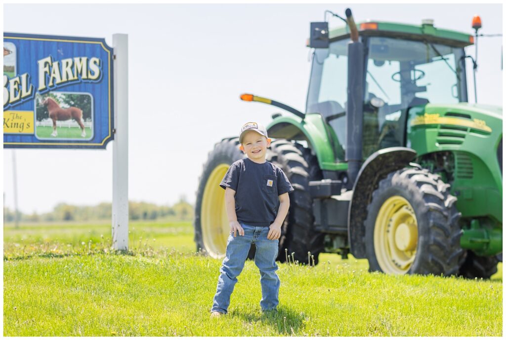 boy posing in front of a green tractor on a farm in Fremont, Ohio