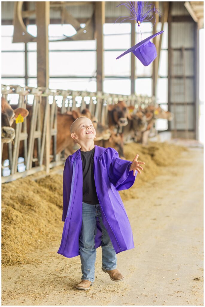 boy throwing his cap in the air inside a cow barn in Sandusky, Ohio