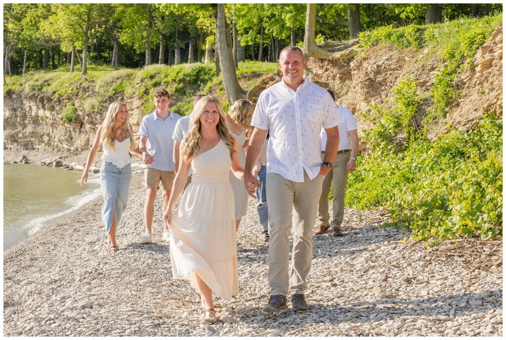 family holding hands and walking along the rocky beach next to the shore at Lake Erie