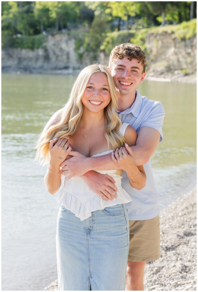 couple hugging and smiling along the water at Lake Erie family session
