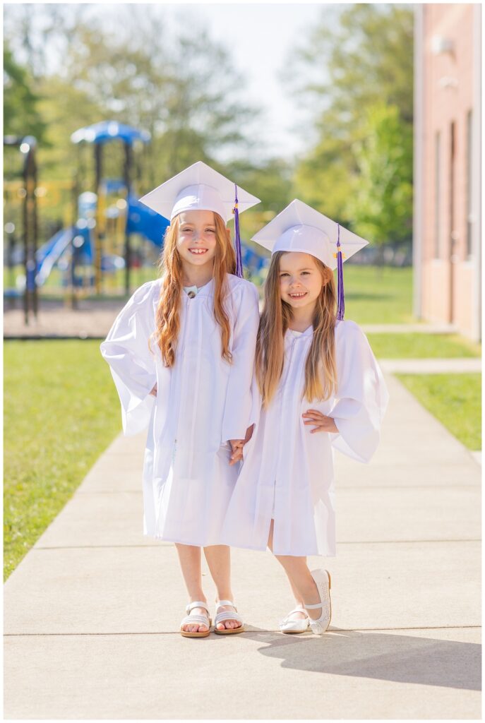 two girls in white graduation gowns posing for a mini session in Fremont, Ohio