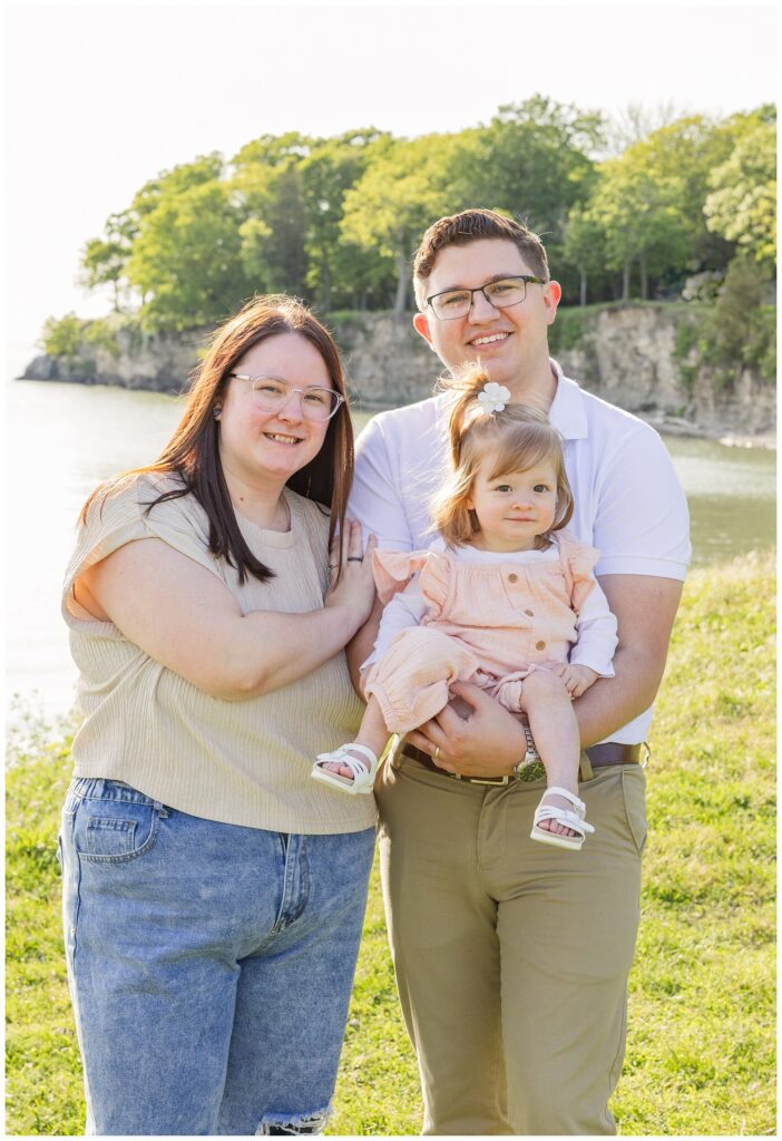 husband and wife holding their daughter and posing on the grass in South Bass Island