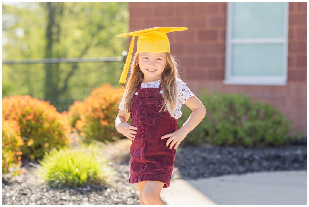 girl wearing a brown jumper and yellow graduation cap at mini session