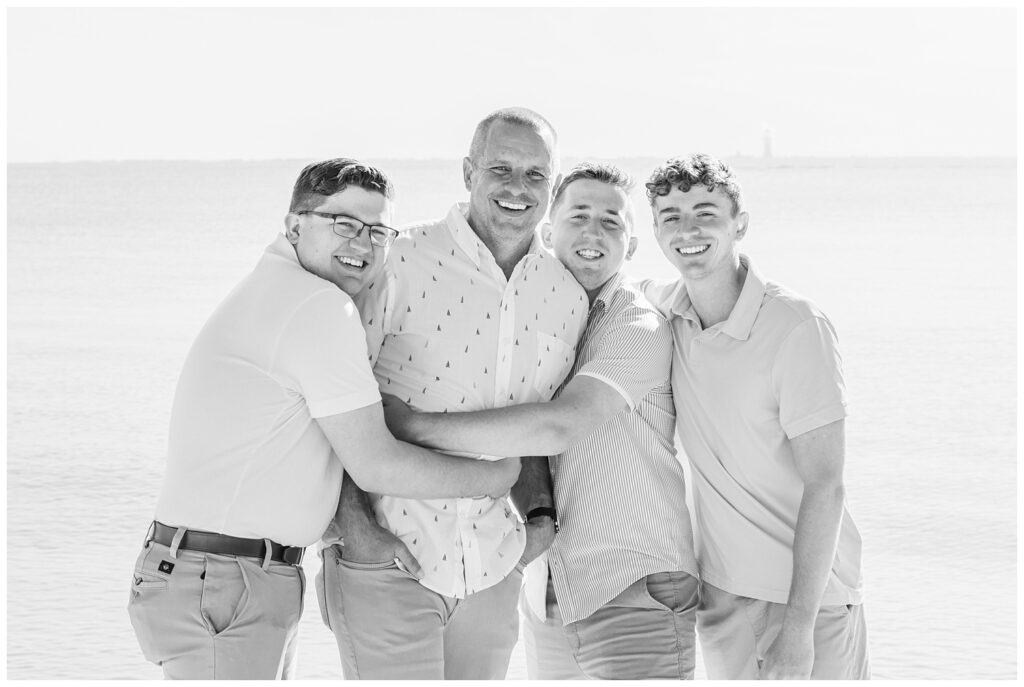 guy members of extended family session hugging on the beach on Lake Erie