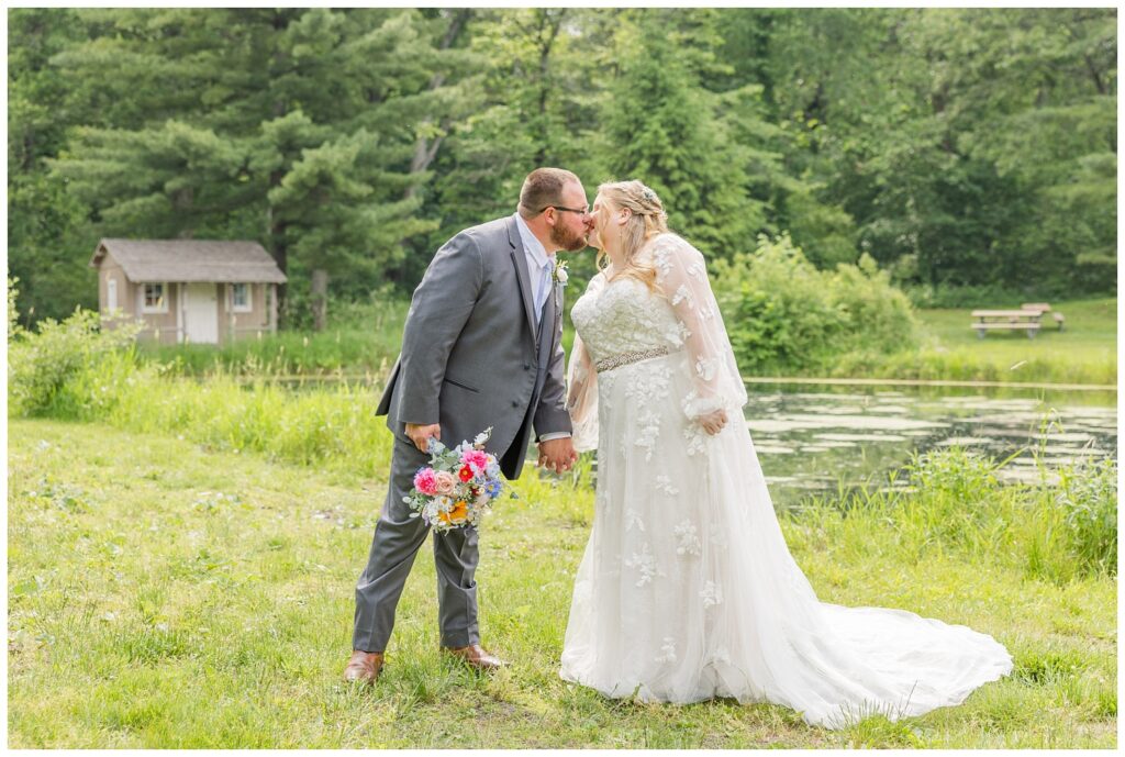 wedding couple share a kiss near the pond at Bradner Preserve