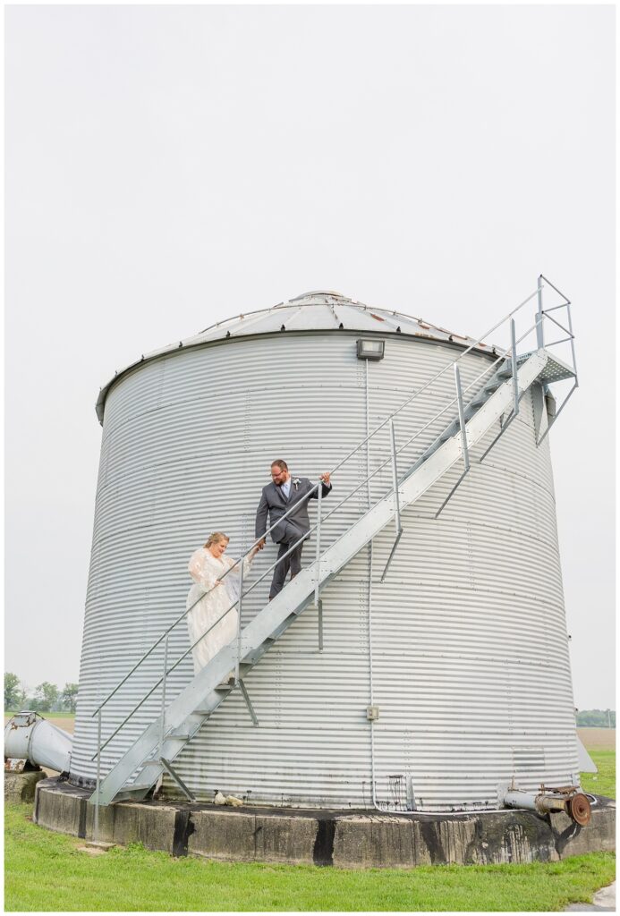 bride and groom posing on the stairs of a grain bin at family farm in Ohio
