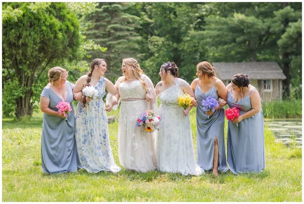 bride walking with her bridesmaids arm in arm and smiling together at Bradner Preserve