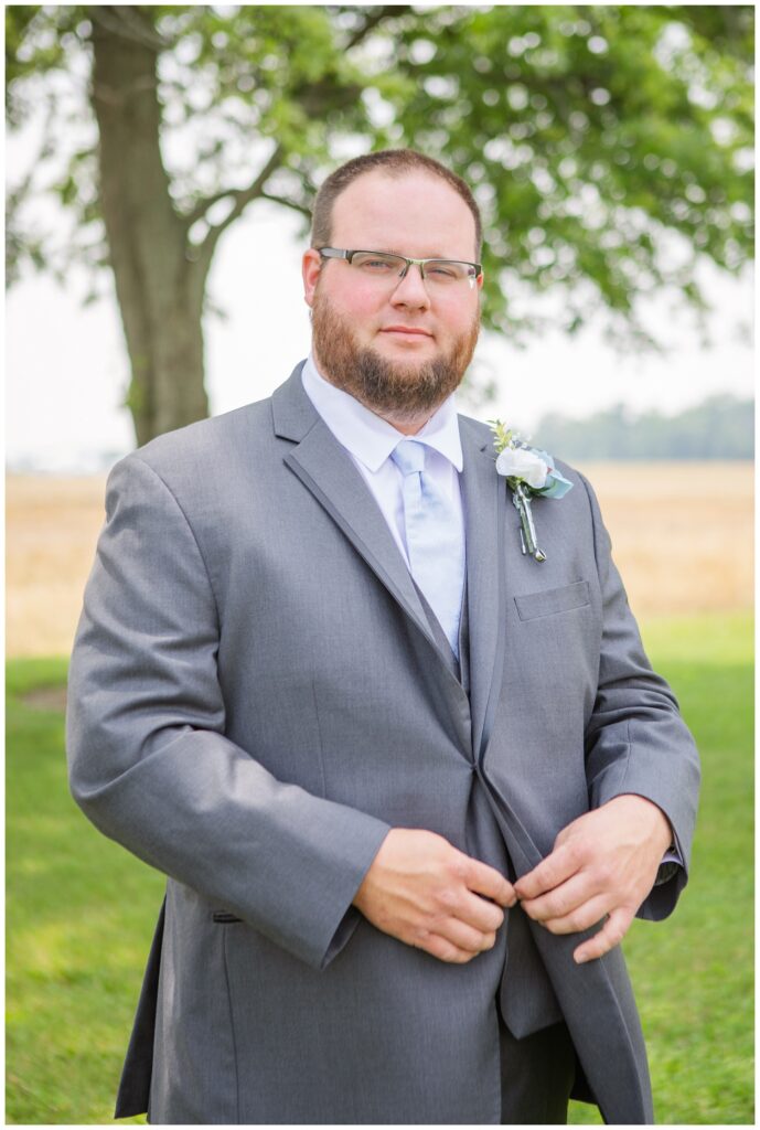 groom adjusting his jacket while getting ready for Fostoria, Ohio wedding