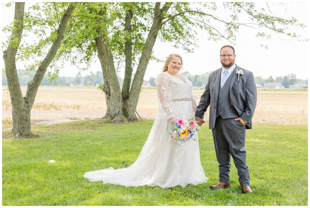 couple holding hands and posing for portraits for summer wedding in Fostoria, Ohio
