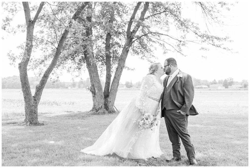 bride and groom sharing a kiss in front of a large tree in Risingsun, Ohio