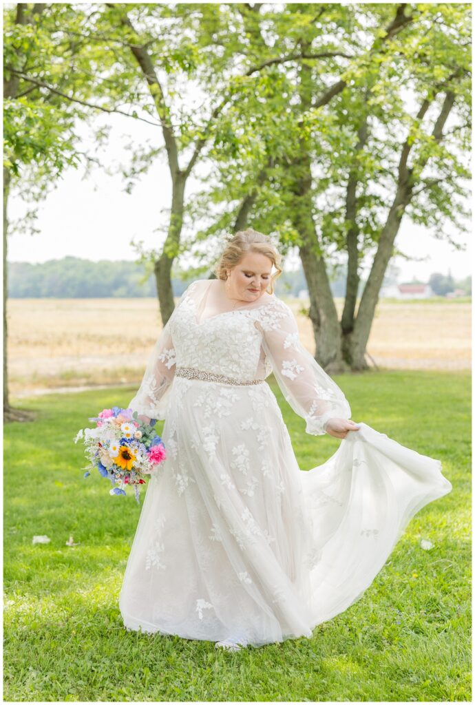 bride holding her train and bouquet while posing at her home in Risingsun, Ohio