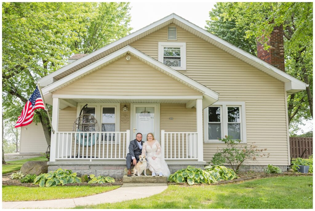 bride and groom posing while holding their dog at their Risingsun, Ohio home