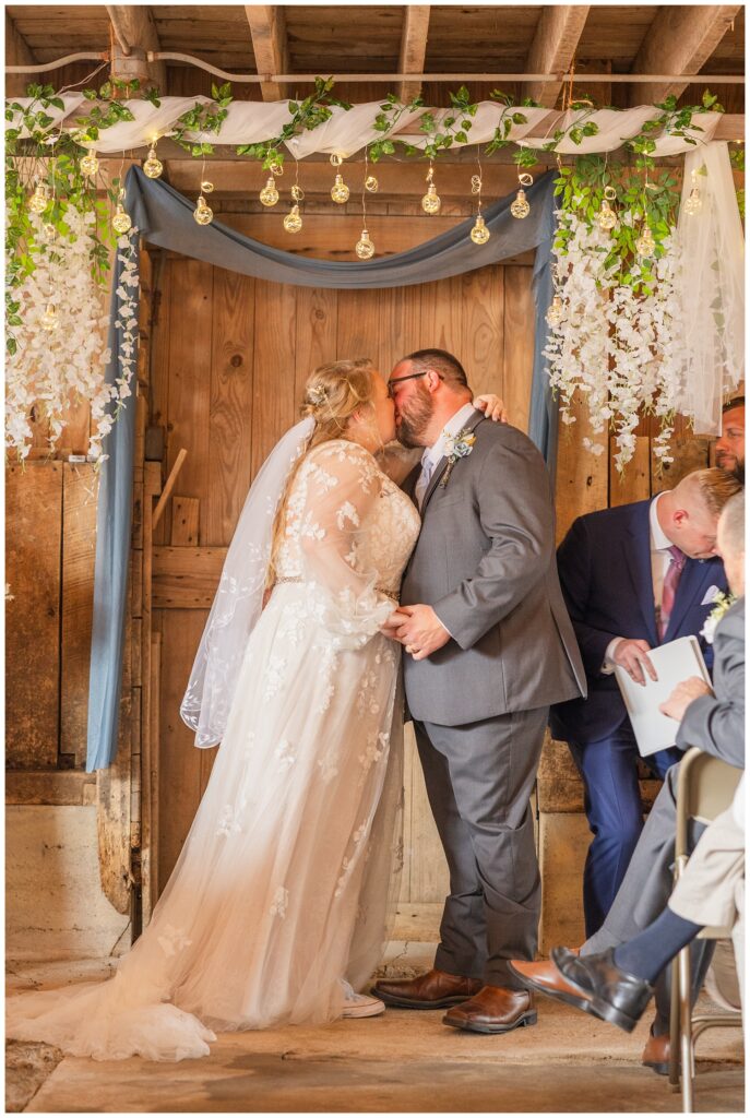 wedding couple share kiss at end of the ceremony at family farm in Fostoria, Ohio
