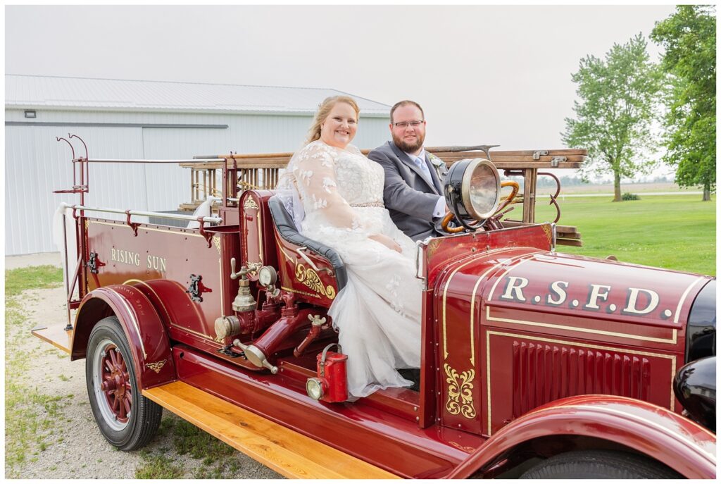 bride and groom smiling in an old vintage fire truck at Fostoria, Ohio wedding