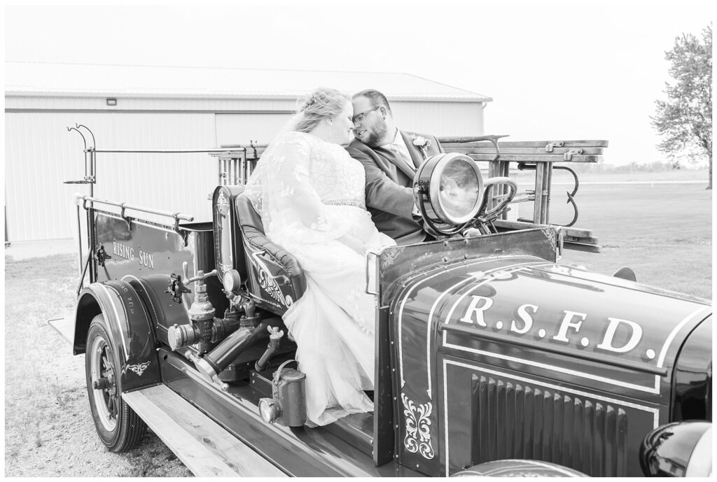 bride and groom posing in an old vintage fire truck at Fostoria, Ohio wedding