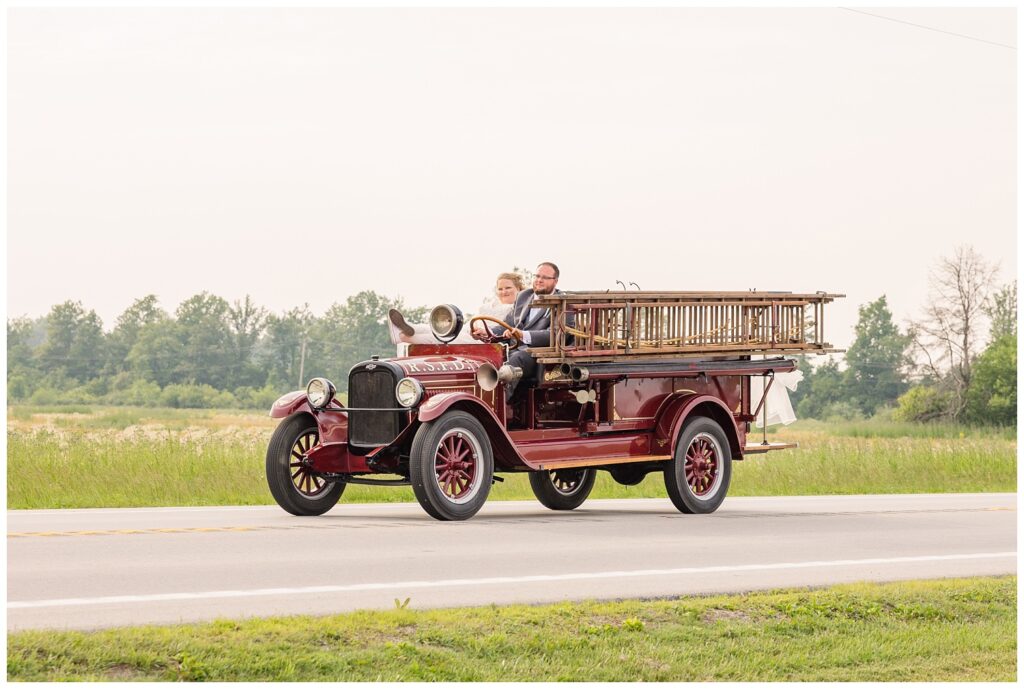 wedding couple taking a ride in a vintage red fire truck from Risingsun, Ohio
