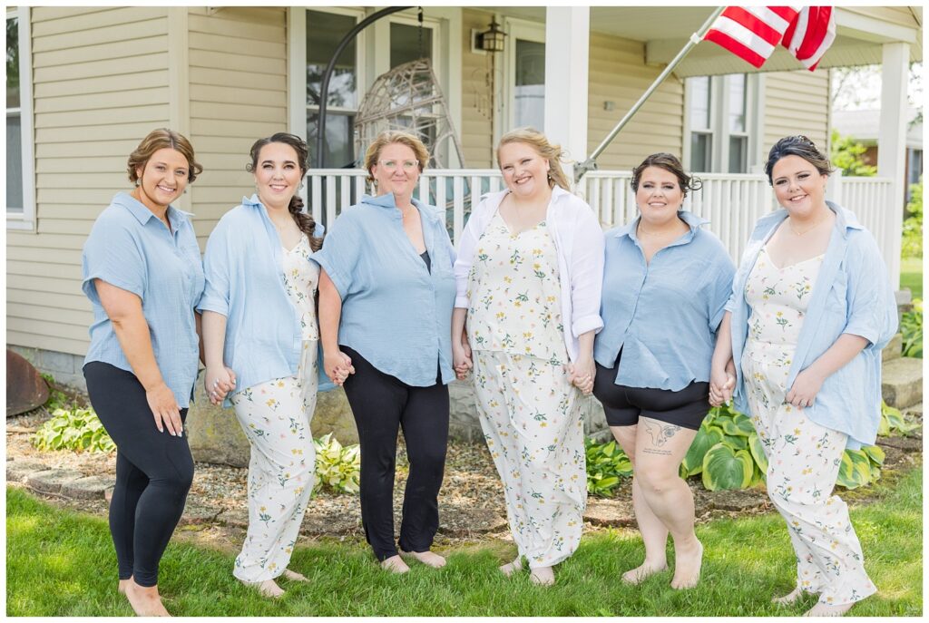 bride and bridal party posing outside the bride's home while getting ready