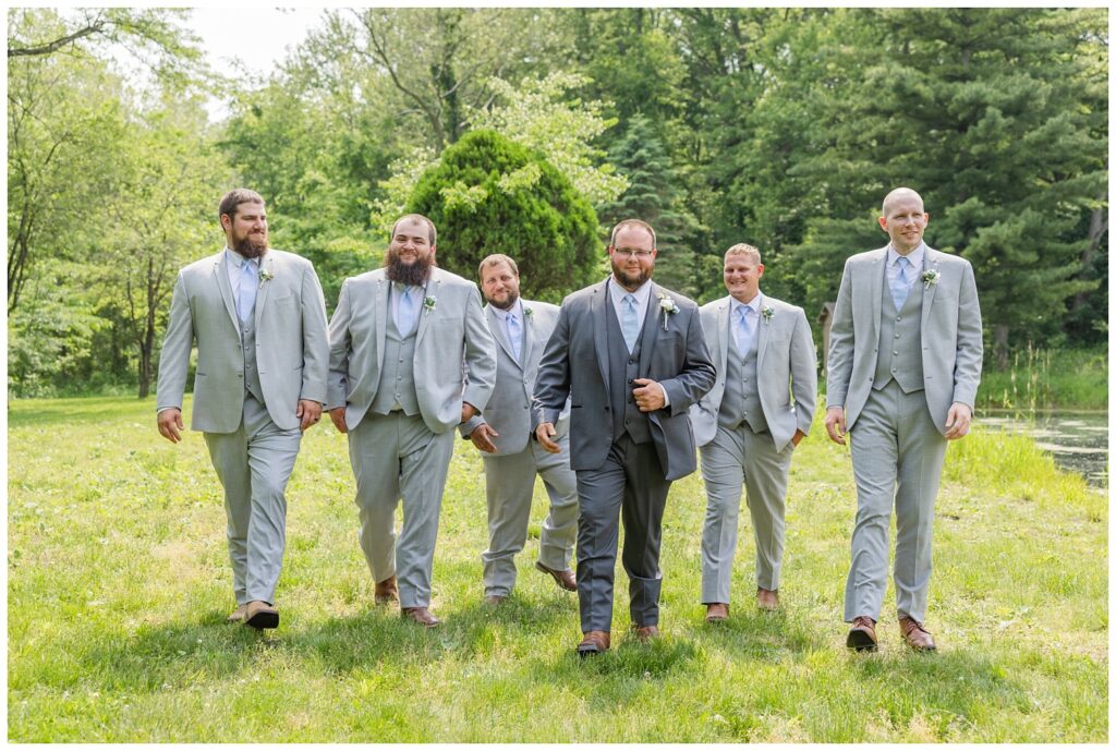 groom and groomsmen walking together near the pond for portraits at Bradner Preserve
