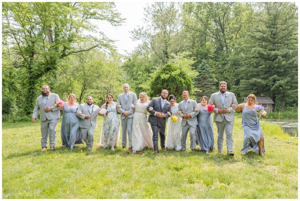 full wedding party walking arm in arm at Bradner Preserve in Ohio