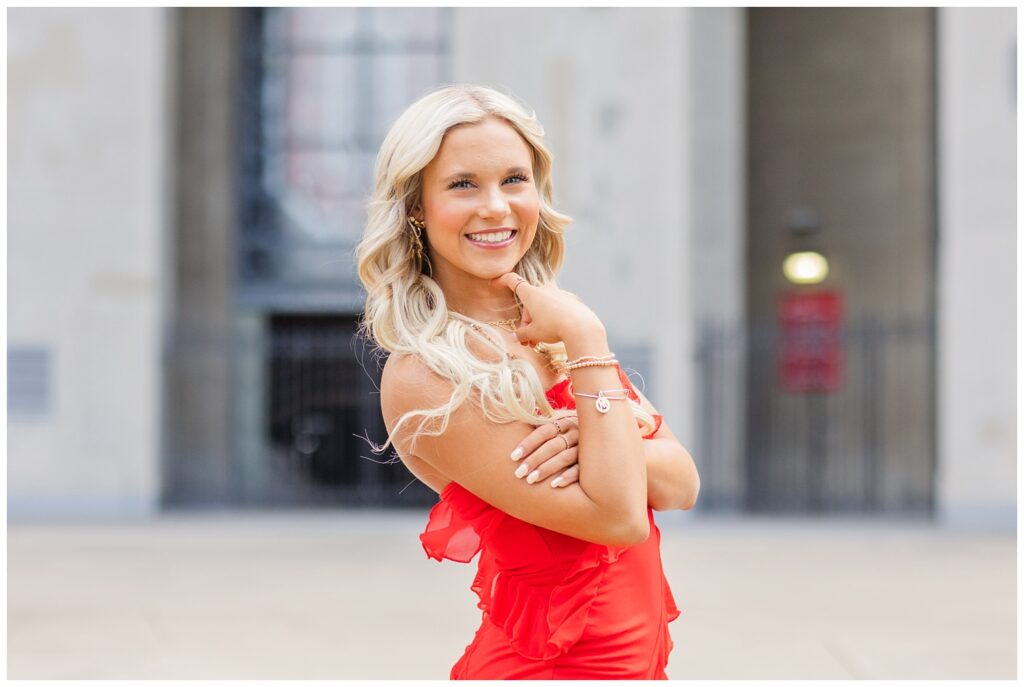 high school senior girl wearing a red strapless dress and posing at Ohio State campus
