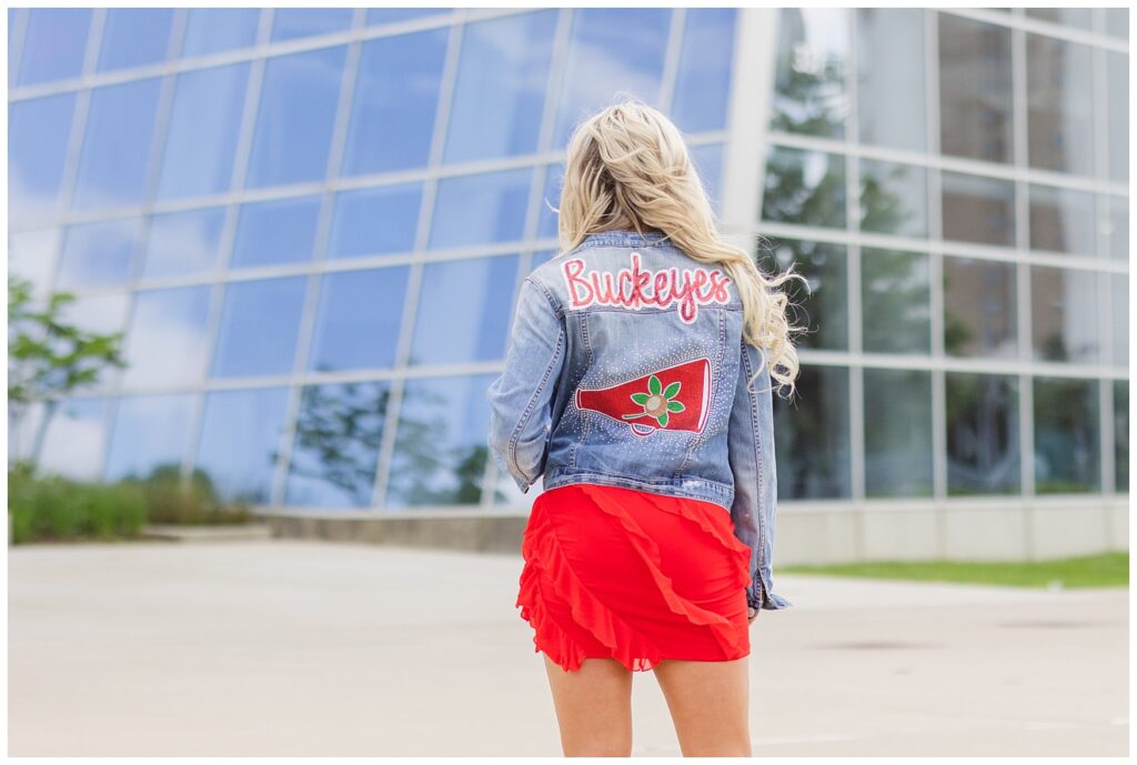 senior girl showing off her Ohio State jean jacket at session in Columbus, Ohio