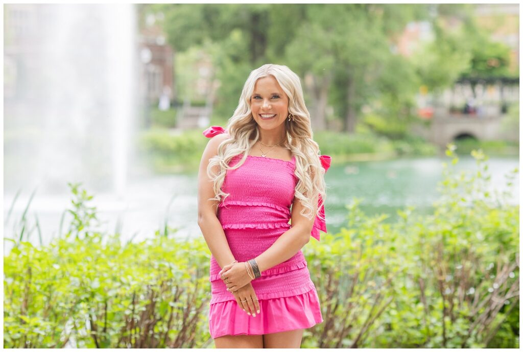 senior girl wearing a pink dress and posing in front of Mirror Lake at Ohio State