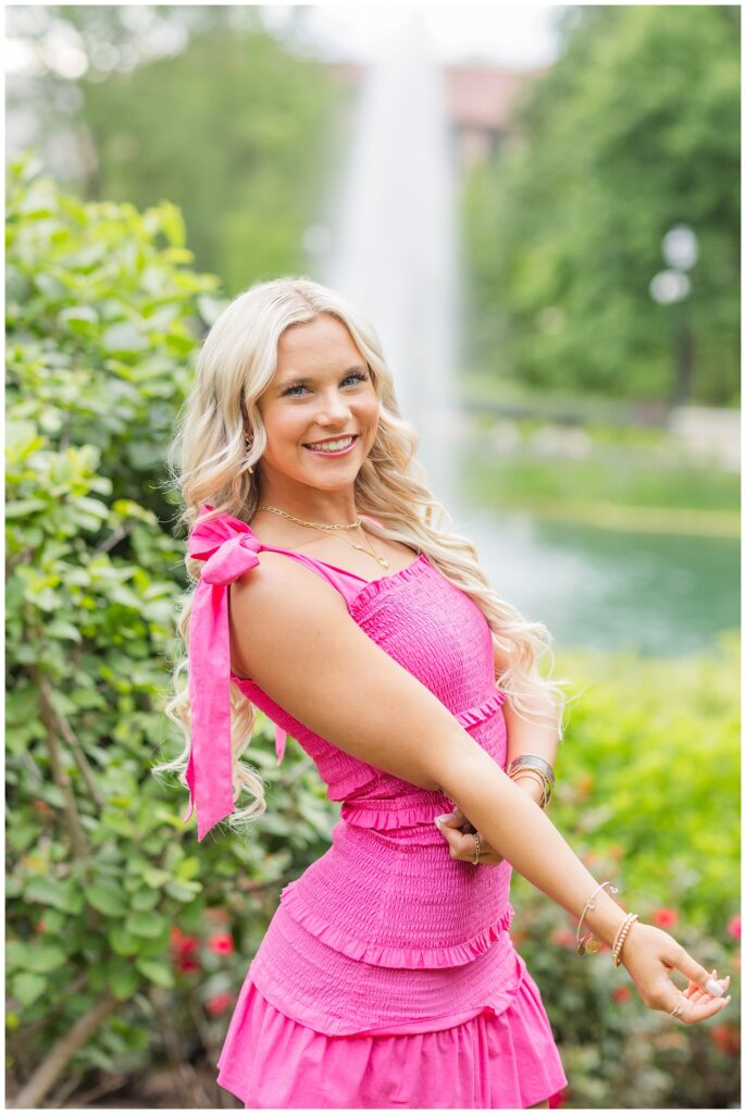 senior girl posing near a bush at the lake at Ohio State campus in Columbus