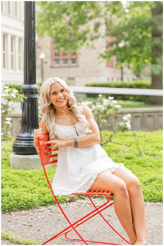 high school senior girl posing on a red chair wearing a white dress at Ohio State