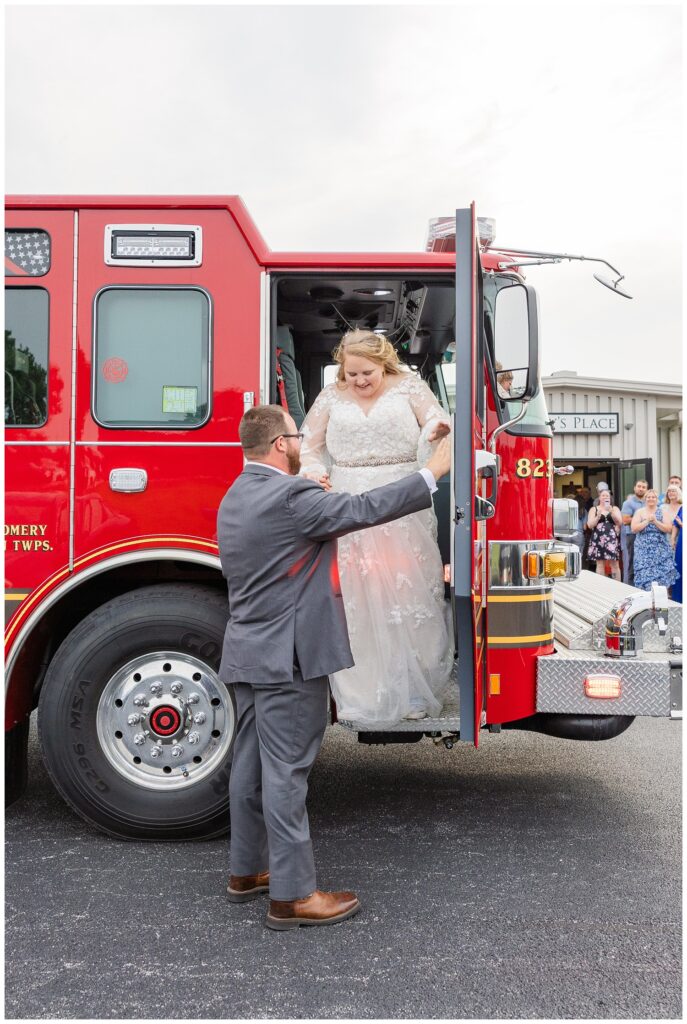 groom helping the bride down from a red fire truck at Fostoria, Ohio wedding reception