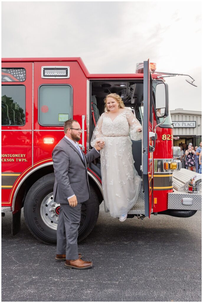 groom helping the bride down from a red fire truck in Fostoria, Ohio