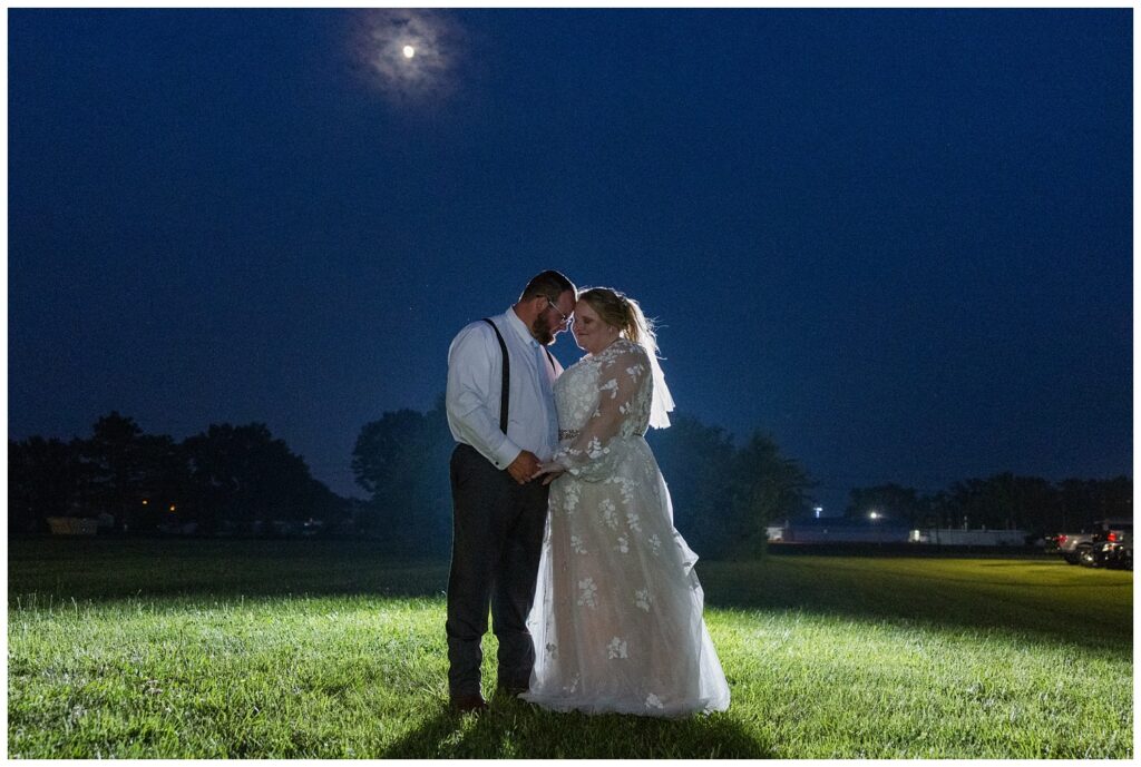 bride and groom holding hands posing under the moon in Fostoria, Ohio