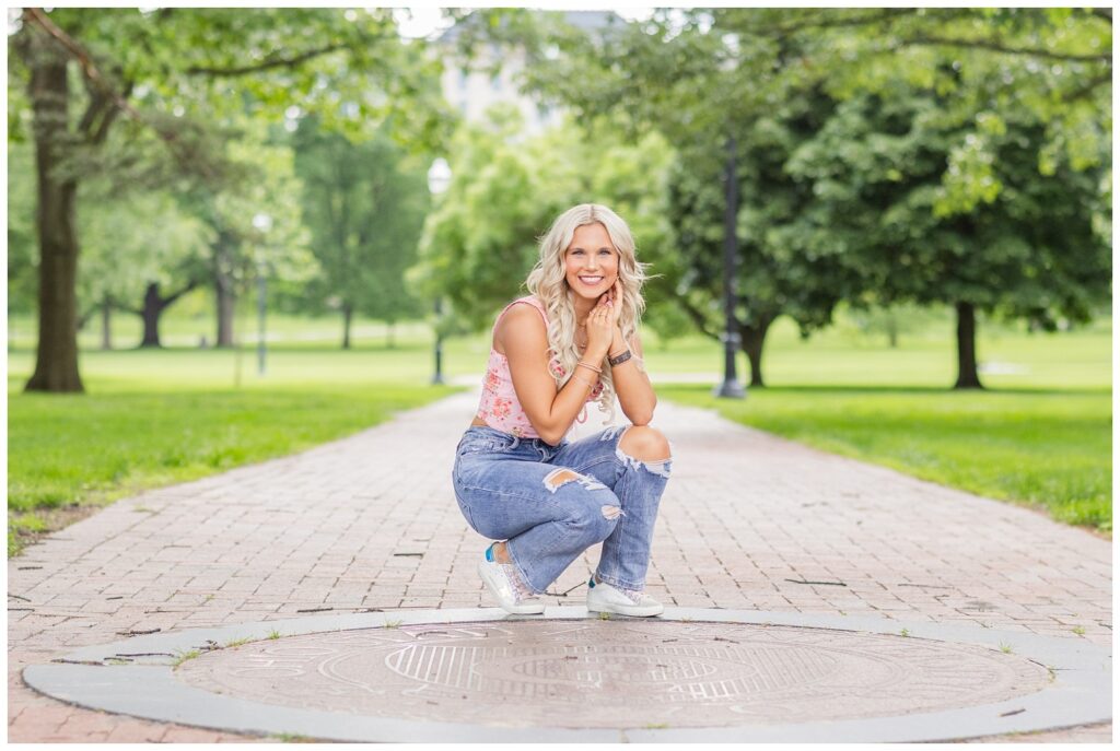 senior girl squatting at The Oval sidewalk at Ohio State in Columbus