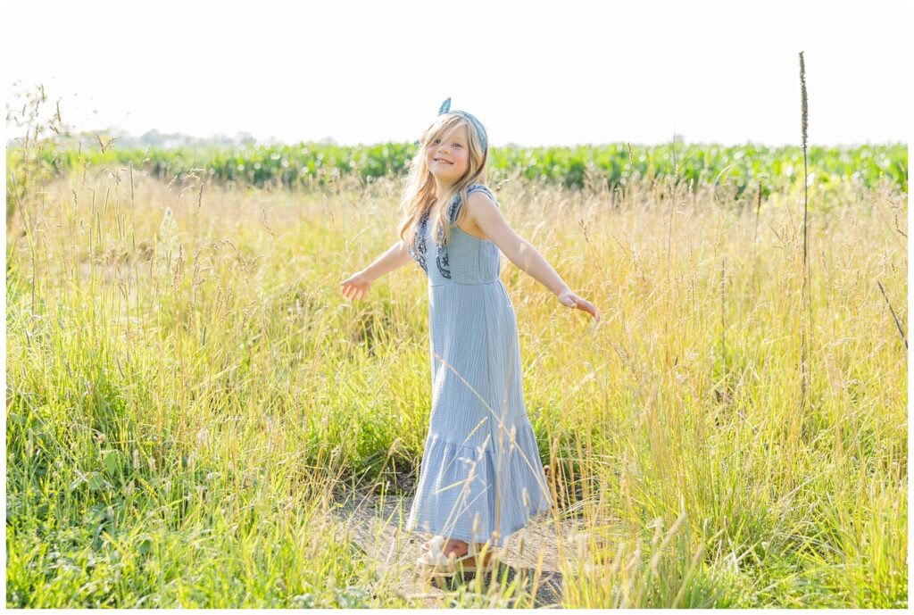 little girl wearing a blue dress spinning around in a large field in Tiffin, Ohio