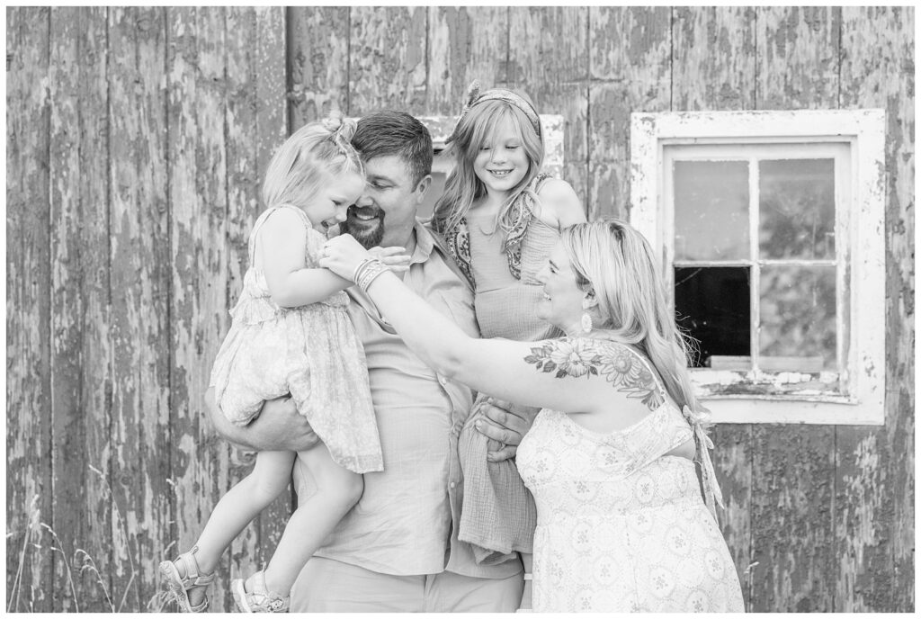 family tickling each other and laughing  while posing in front of a red barn in Fremont, Ohio