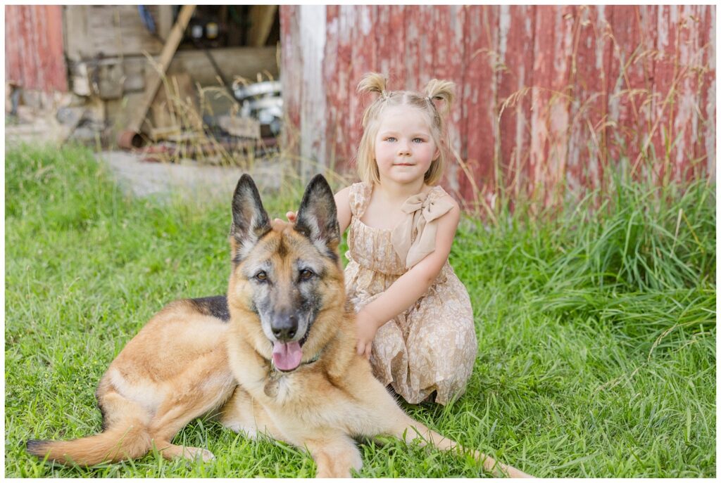 little girl sitting in the grass next to one of her dogs in Fremont, Ohio