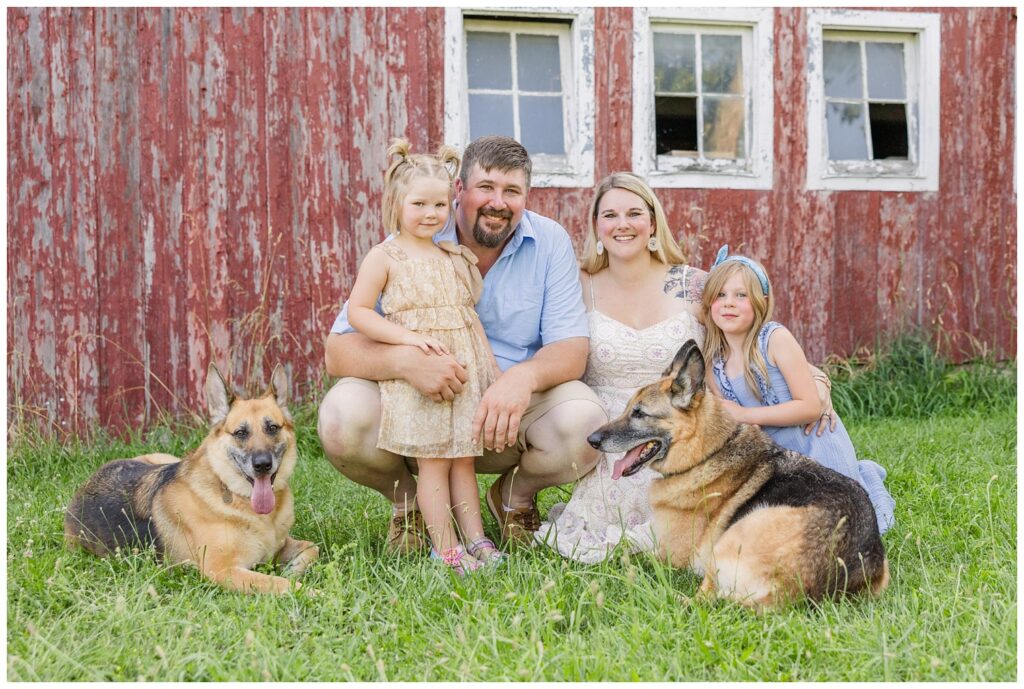 family kneeling on the ground with their dogs and two daughters with Fremont, Ohio photographer