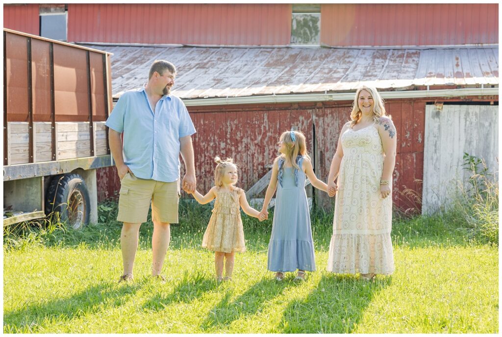 family posing and holding hands in front of a red barn in Fremont, Ohio