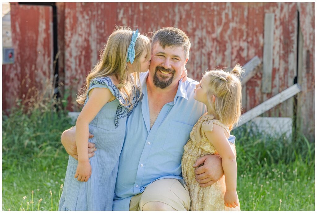 dad kneeling down holding his daughters at farm family session in Fremont, Ohio