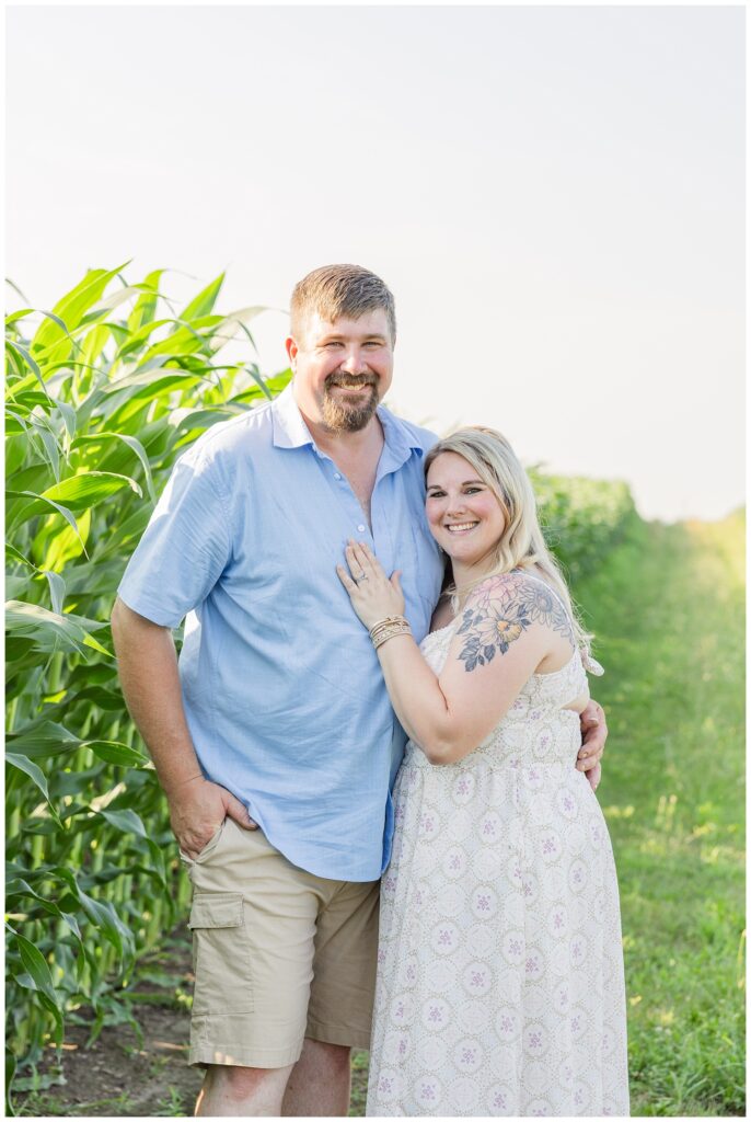 mom and dad smiling and hugging next to corn stalks for Tiffin, Ohio family session